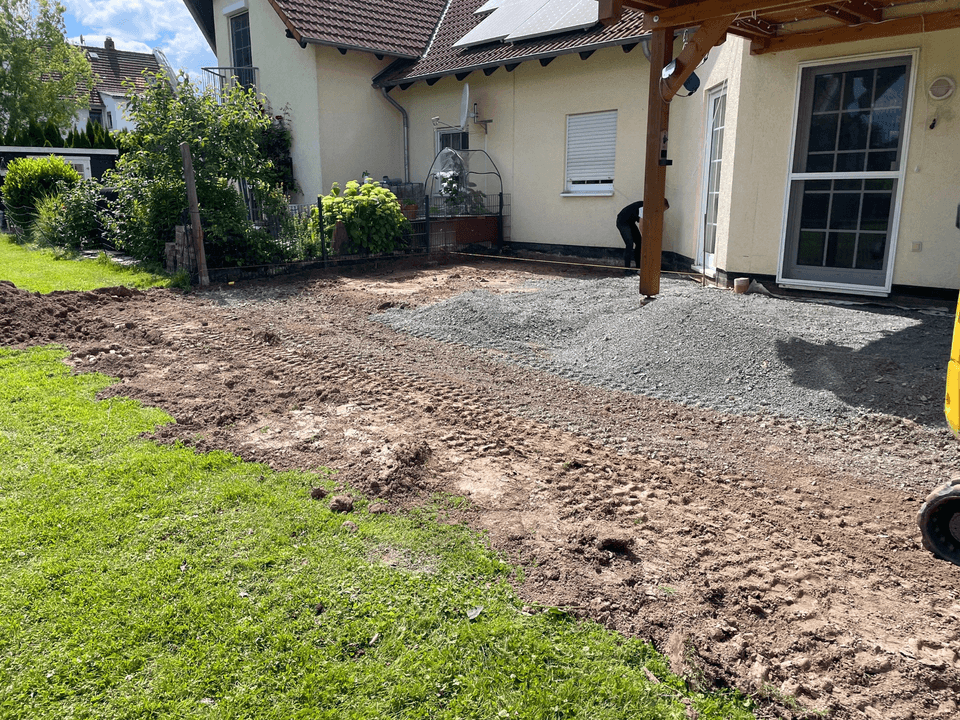 Vorbereitete Außenfläche mit Schotter und Erdarbeiten an einem Wohnhaus