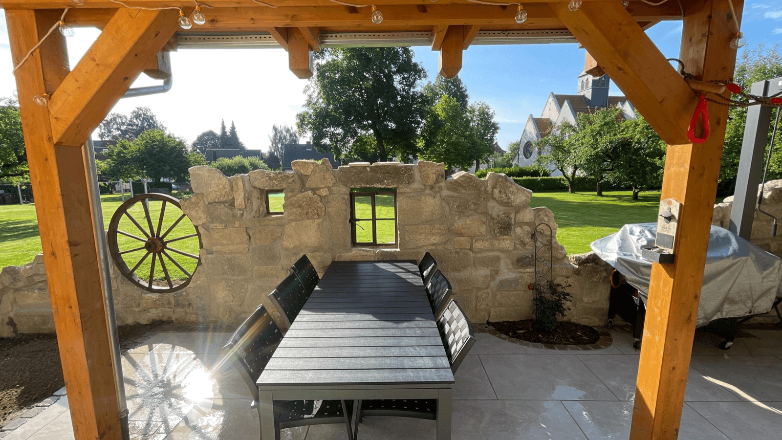 Fertige Terrasse mit Natursteinmauer, Sitzbereich und Blick in einen grünen Garten