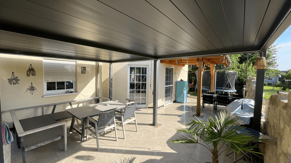 Überdachte Terrasse mit gereinigten Fliesen und gepflegtem Außenbereich
